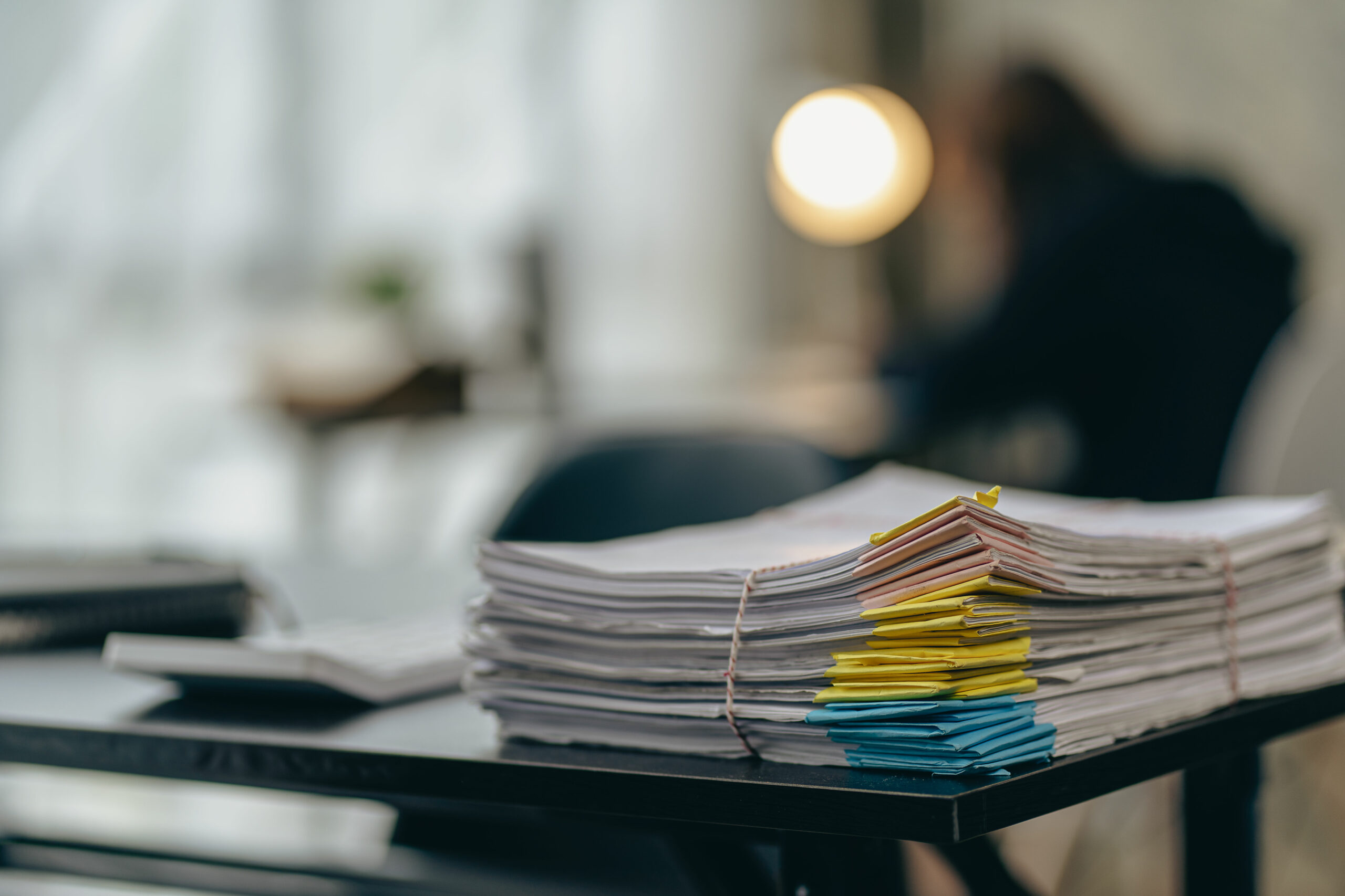 a pile of papers lying on the business desk in the office Archived documents with paper clips on the table. The unfinished information is in the building near the window. business idea